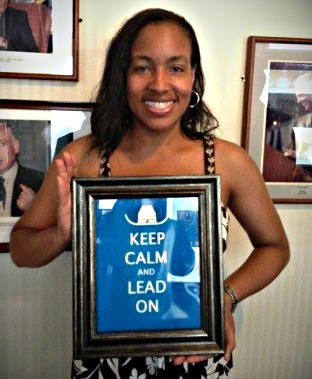 Kamilah smiles and holds a frame that says, keep calm and lead on