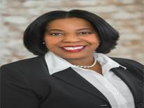Hope smiles wearing black blazer, white button down, pearl necklace